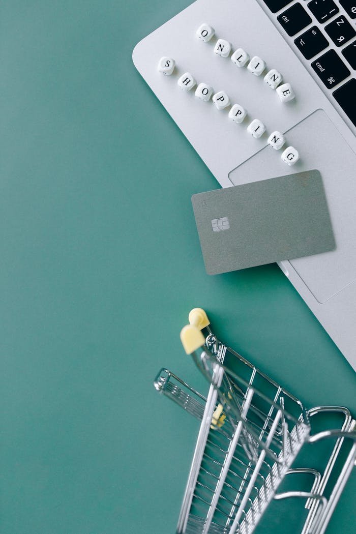 Image showcasing online shopping with a laptop, bank card, and mini cart.